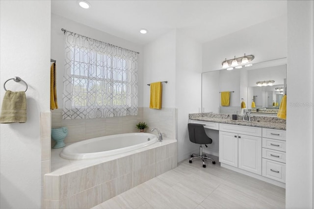 bathroom with vanity, a relaxing tiled tub, and tile patterned flooring