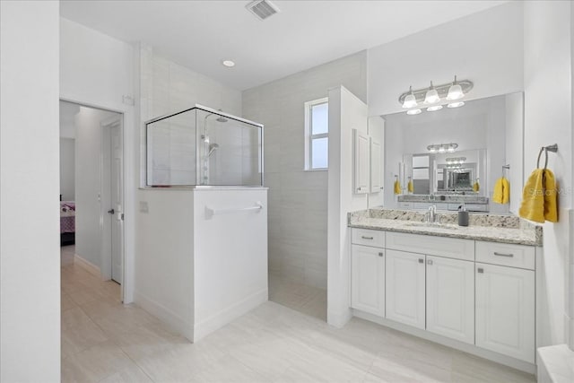 bathroom with vanity, a tile shower, and tile patterned flooring