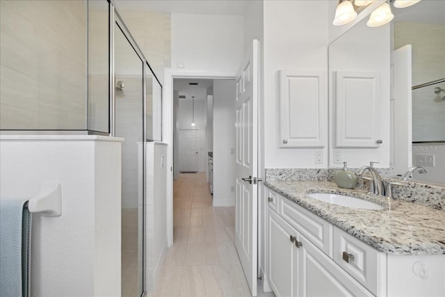 bathroom featuring a shower with door, tile patterned flooring, and vanity