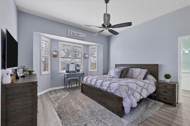 bedroom with light hardwood / wood-style floors, ceiling fan, and connected bathroom