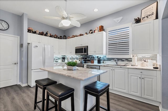 kitchen featuring white cabinets, decorative backsplash, appliances with stainless steel finishes, and light stone counters