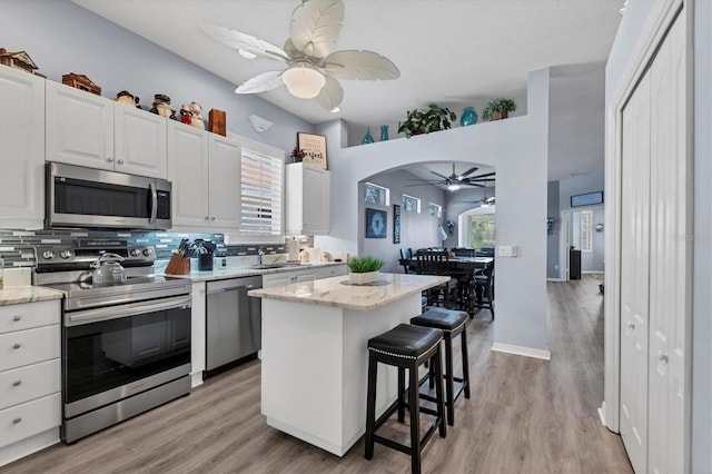 kitchen featuring white cabinets, appliances with stainless steel finishes, a breakfast bar, and a center island