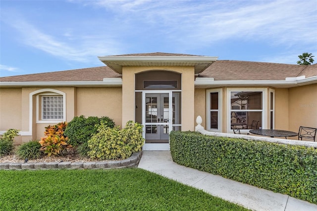 entrance to property with a lawn and french doors