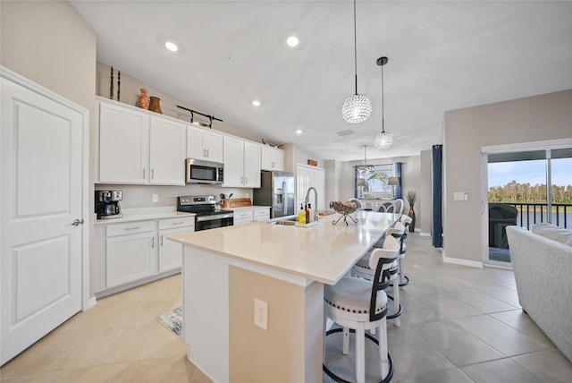 kitchen with appliances with stainless steel finishes, a kitchen island with sink, and white cabinets