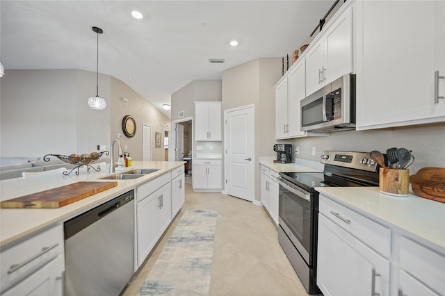 kitchen with white cabinets, vaulted ceiling, sink, decorative light fixtures, and stainless steel appliances