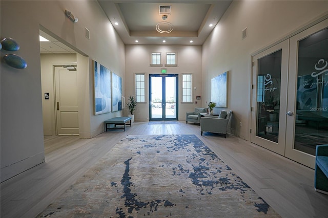 entryway with french doors, light hardwood / wood-style flooring, and a high ceiling