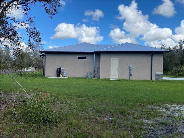 rear view of house featuring a lawn and cooling unit