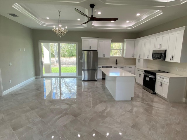 kitchen featuring appliances with stainless steel finishes, a center island, white cabinetry, and a healthy amount of sunlight