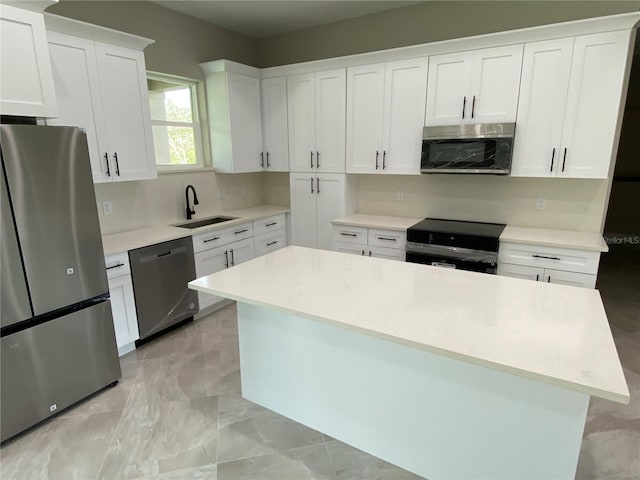 kitchen with white cabinetry, a center island, stainless steel appliances, and sink