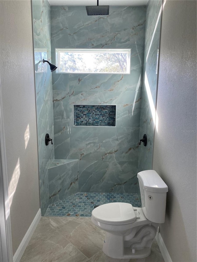 bathroom with a tile shower, a wealth of natural light, and toilet