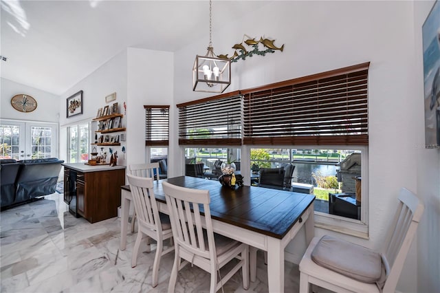 dining area with high vaulted ceiling, a water view, an inviting chandelier, and french doors