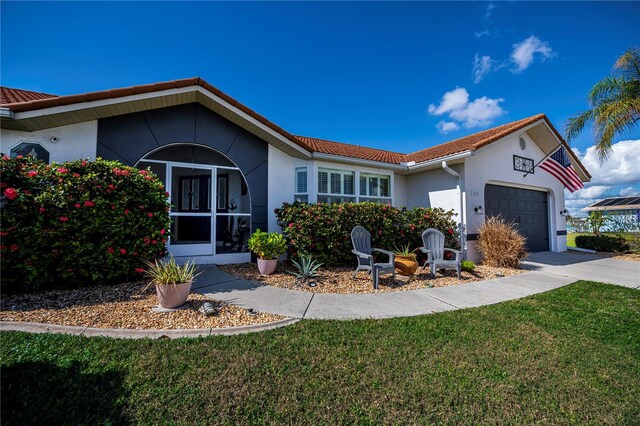 view of front of property with a garage, driveway, a front lawn, and stucco siding