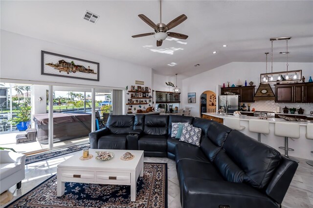 living area featuring visible vents, lofted ceiling, arched walkways, and ceiling fan