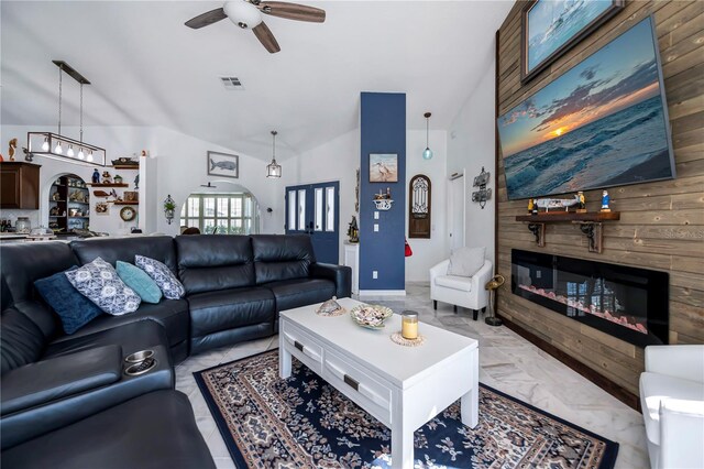 living area featuring visible vents, marble finish floor, a ceiling fan, a glass covered fireplace, and vaulted ceiling