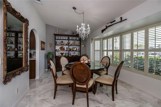 dining area with baseboards, vaulted ceiling, an inviting chandelier, arched walkways, and marble finish floor