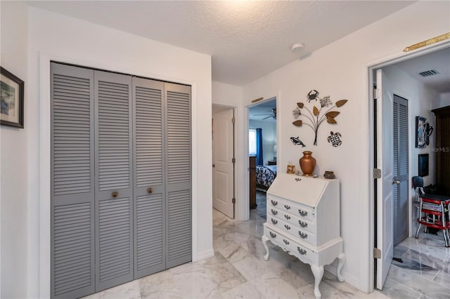 corridor featuring visible vents, marble finish floor, and a textured ceiling