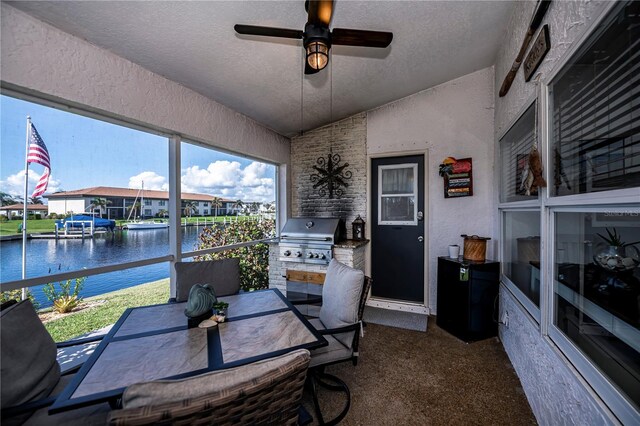 exterior space featuring a water view, a textured ceiling, a textured wall, ceiling fan, and vaulted ceiling