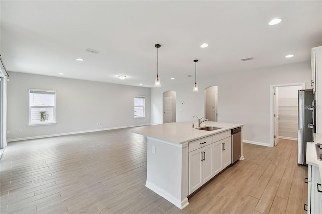 kitchen featuring white cabinetry, light wood-type flooring, pendant lighting, and an island with sink