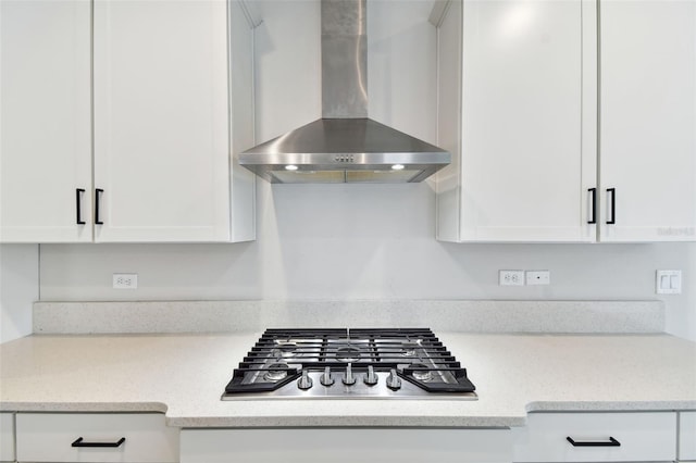 kitchen with white cabinetry, wall chimney exhaust hood, stainless steel gas stovetop, and light stone counters