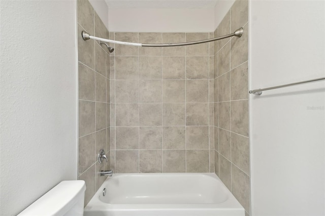 bathroom featuring tiled shower / bath and toilet