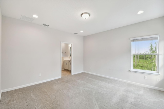 unfurnished bedroom featuring ensuite bath and light carpet