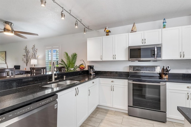 kitchen featuring stainless steel appliances, sink, dark stone countertops, and white cabinets