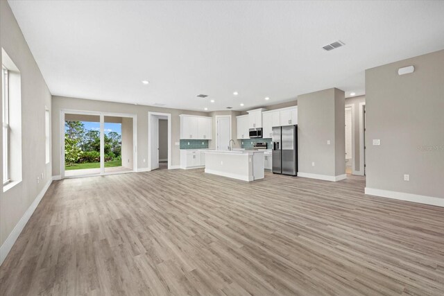 unfurnished living room with sink and light hardwood / wood-style flooring