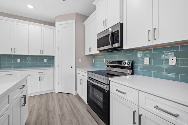 kitchen featuring white cabinetry, stainless steel appliances, light wood-type flooring, and tasteful backsplash