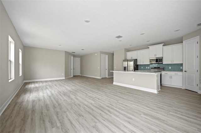 3883 Dominic St, North Port, FL 34288 - kitchen with decorative backsplash, a kitchen island with sink, appliances with stainless steel finishes, baseboards, and open floor plan