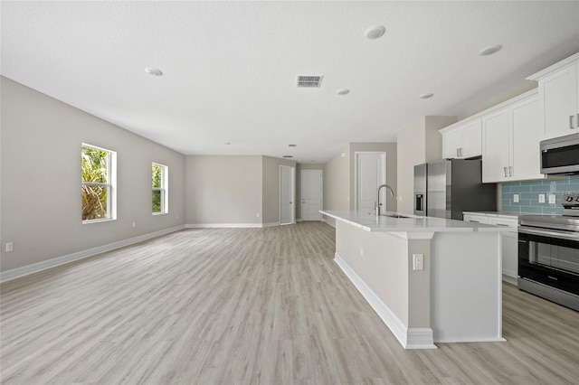 3883 Dominic St, North Port, FL 34288 - kitchen featuring visible vents, light wood-style floors, a center island with sink, light countertops, and stainless steel appliances