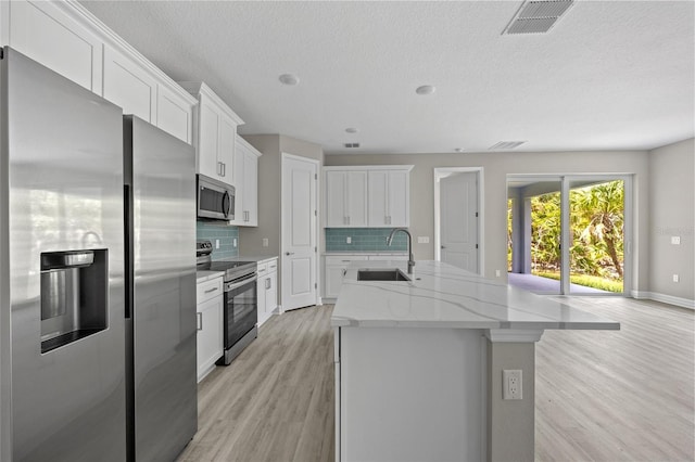 3883 Dominic St, North Port, FL 34288 - kitchen featuring appliances with stainless steel finishes, a sink, a kitchen island with sink, light wood-style flooring, and visible vents