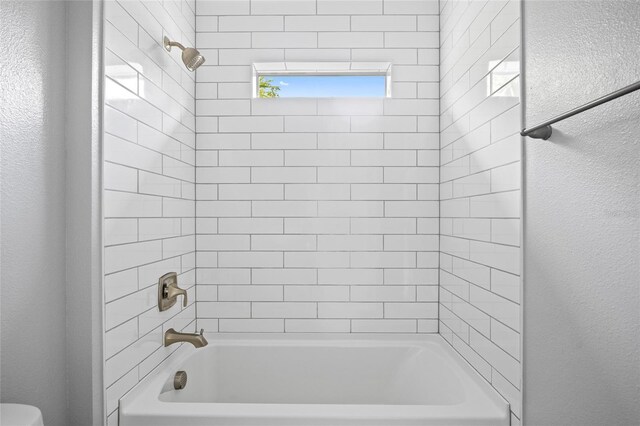 3883 Dominic St, North Port, FL 34288 - bathroom featuring washtub / shower combination, a textured wall, and toilet