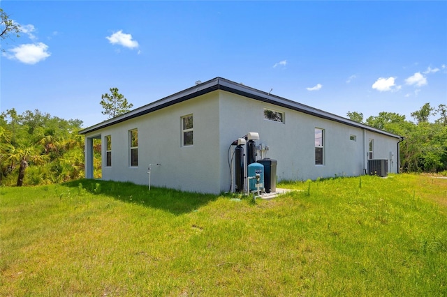 3883 Dominic St, North Port, FL 34288 - view of side of property with central air condition unit, a lawn, and stucco siding