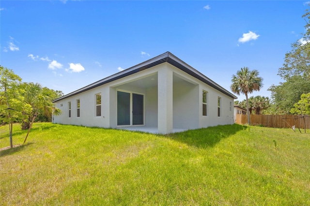3883 Dominic St, North Port, FL 34288 - rear view of house featuring fence, stucco siding, and a lawn
