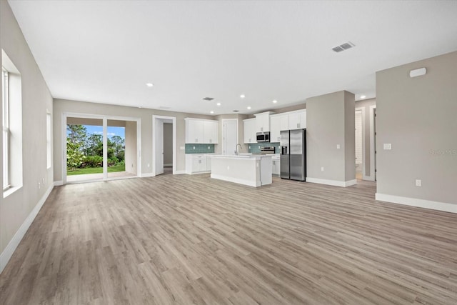 unfurnished living room with light hardwood / wood-style floors and sink