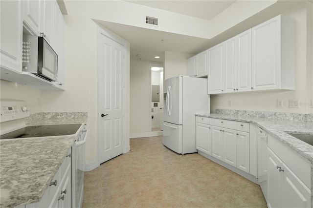 kitchen with white cabinets, light tile patterned floors, white appliances, and light stone counters