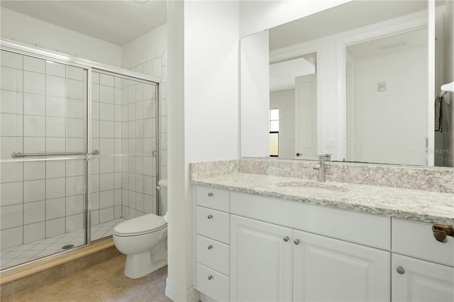 bathroom with tile patterned floors, vanity, toilet, and a shower with door