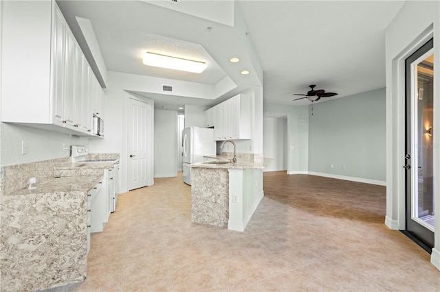 kitchen with kitchen peninsula, white appliances, ceiling fan, sink, and white cabinetry