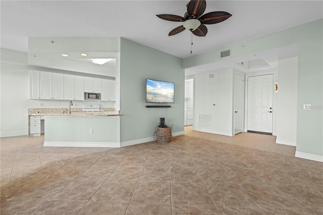 unfurnished living room featuring ceiling fan, sink, and light tile patterned floors