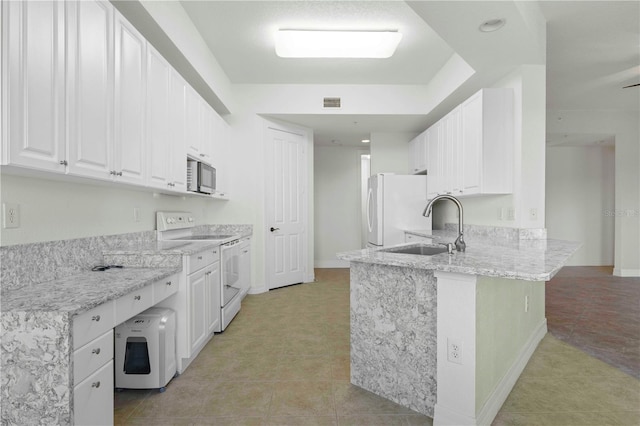 kitchen with kitchen peninsula, light stone countertops, white appliances, sink, and white cabinets