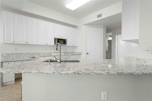 kitchen featuring white cabinets, sink, white fridge, light stone counters, and kitchen peninsula