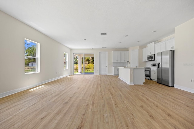 3779 Clearfield St, North Port, FL 34286 - unfurnished living room with baseboards, light wood finished floors, and visible vents