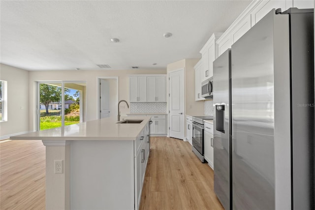 3779 Clearfield St, North Port, FL 34286 - kitchen featuring appliances with stainless steel finishes, a sink, a kitchen island with sink, light wood-style flooring, and backsplash