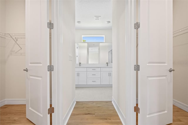 3779 Clearfield St, North Port, FL 34286 - hallway with a sink, baseboards, light wood-type flooring, and visible vents