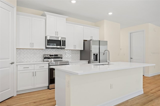1415 Nackman Rd, North Port, FL 34288 - kitchen with stainless steel appliances, an island with sink, a sink, white cabinets, and decorative backsplash