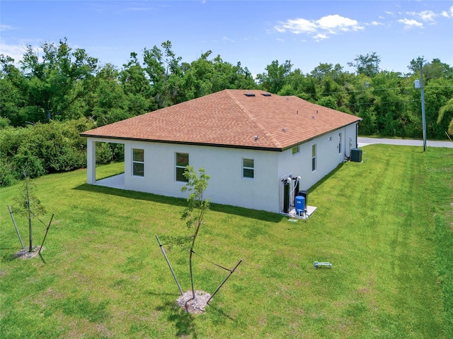 1415 Nackman Rd, North Port, FL 34288 - view of side of home with stucco siding, a yard, central AC, and roof with shingles