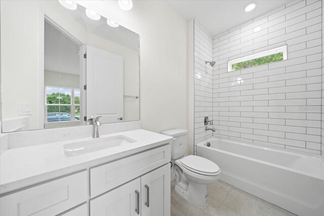 full bathroom featuring tile patterned floors, vanity, tiled shower / bath combo, and toilet