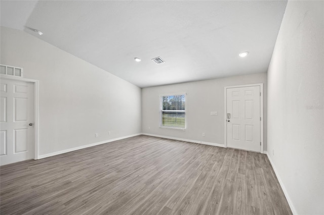 unfurnished room with wood-type flooring and vaulted ceiling