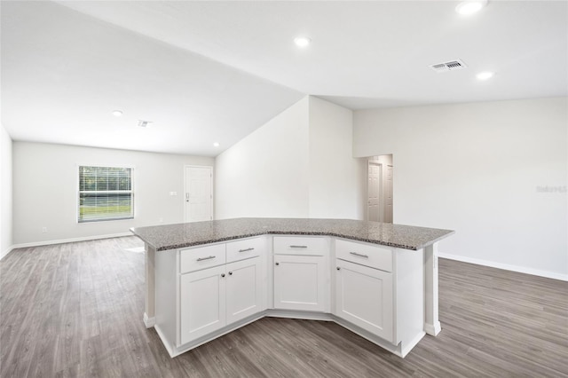 kitchen featuring white cabinets, hardwood / wood-style floors, a center island, and light stone countertops