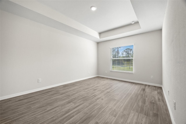 unfurnished room featuring a tray ceiling and hardwood / wood-style floors